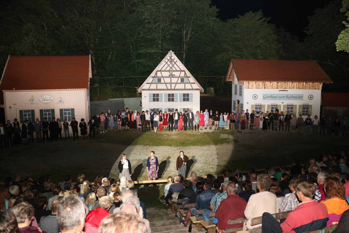 Blick auf eine Theateraufführung bei Nacht im Freien.