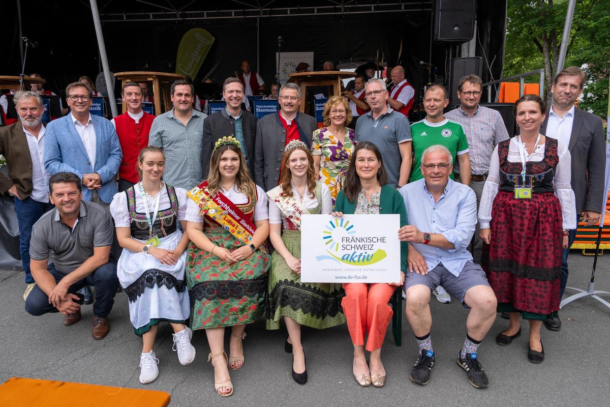 Eine Gruppe von Personen hält ein Schild mit dem Logo der ILE