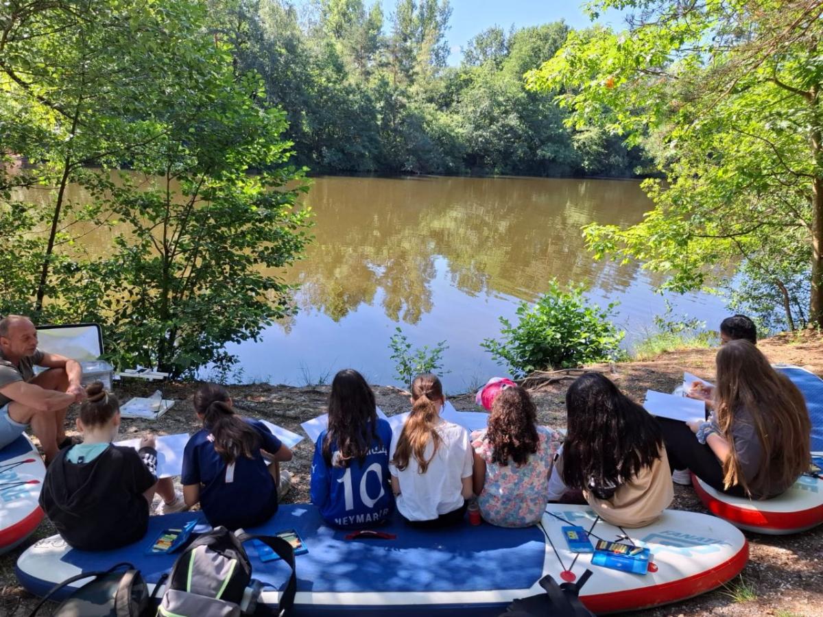 Eine Kindergruppe sitzt an einem See