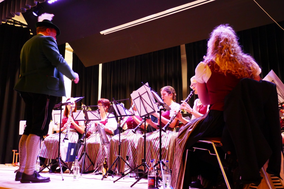 Eine traditionell  bayerische Blaskapelle spielt auf einer Bühne.