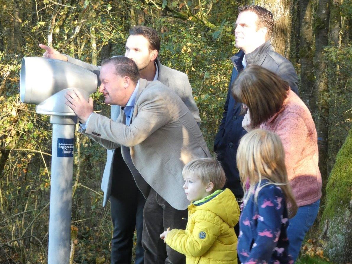 Erwachsene und Kinder haben sich um eine Metallsäule geschart, auf die ein Fernrohr mit extrem großem Linsendurchmesser montiert ist.