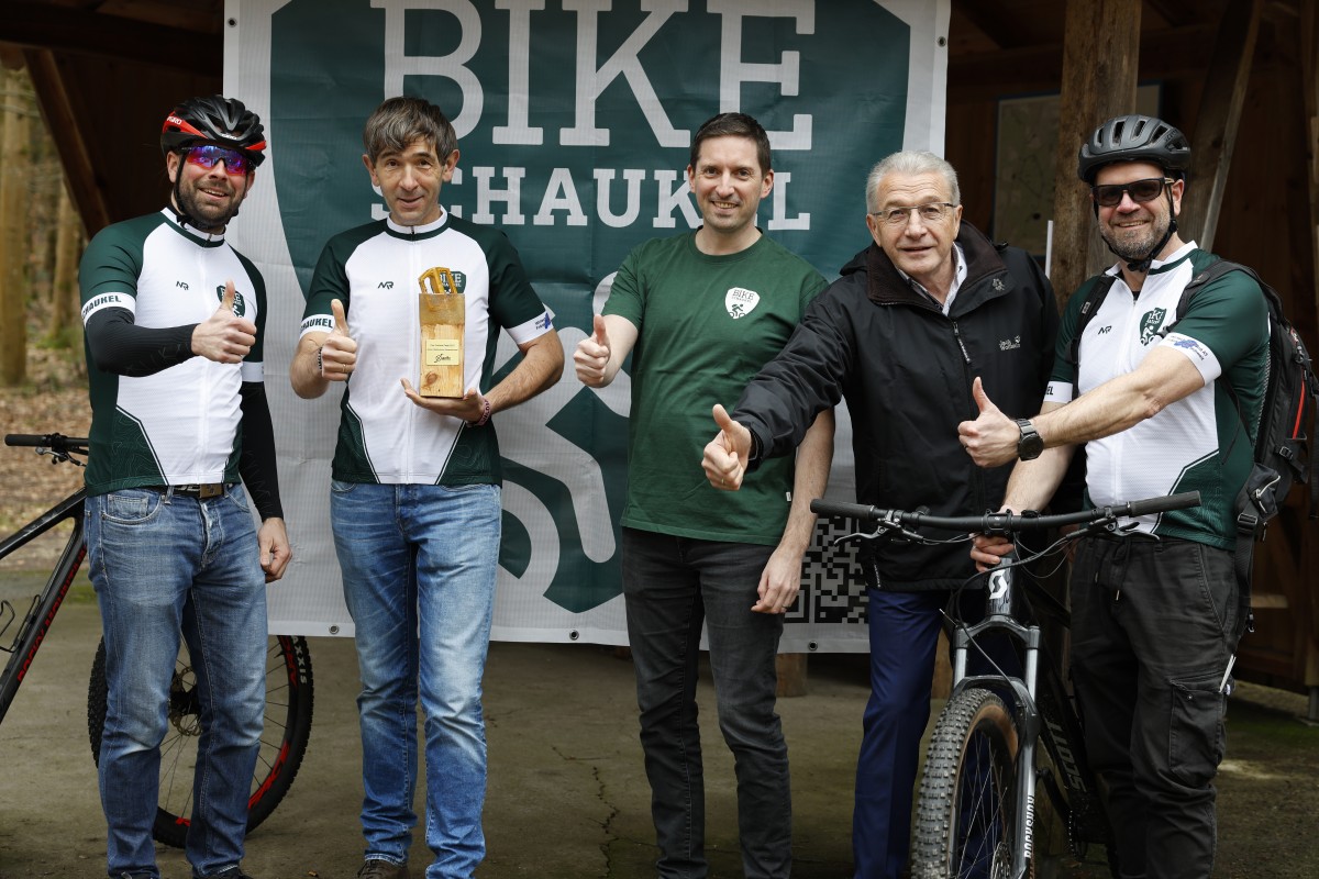 Fünf Personen stehen nebeinander vor einem Schild mit der Aufschrift Bike-Schaukel