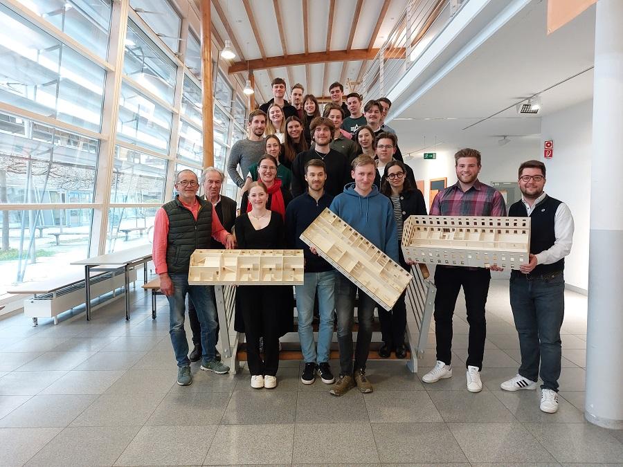 Ein Gruppenbild von Studierenden auf einer Treppe, die Modelle in der Hand halten.